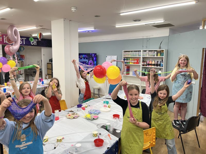 Children cheering with balloons at a painting birthday party in the studio