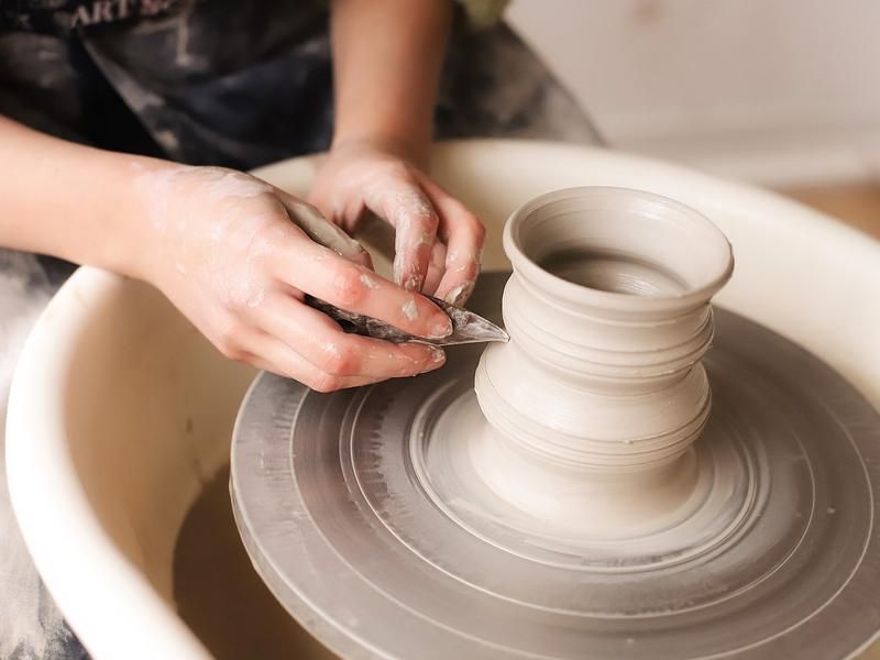 Hands shaping a pot on the pottery wheel