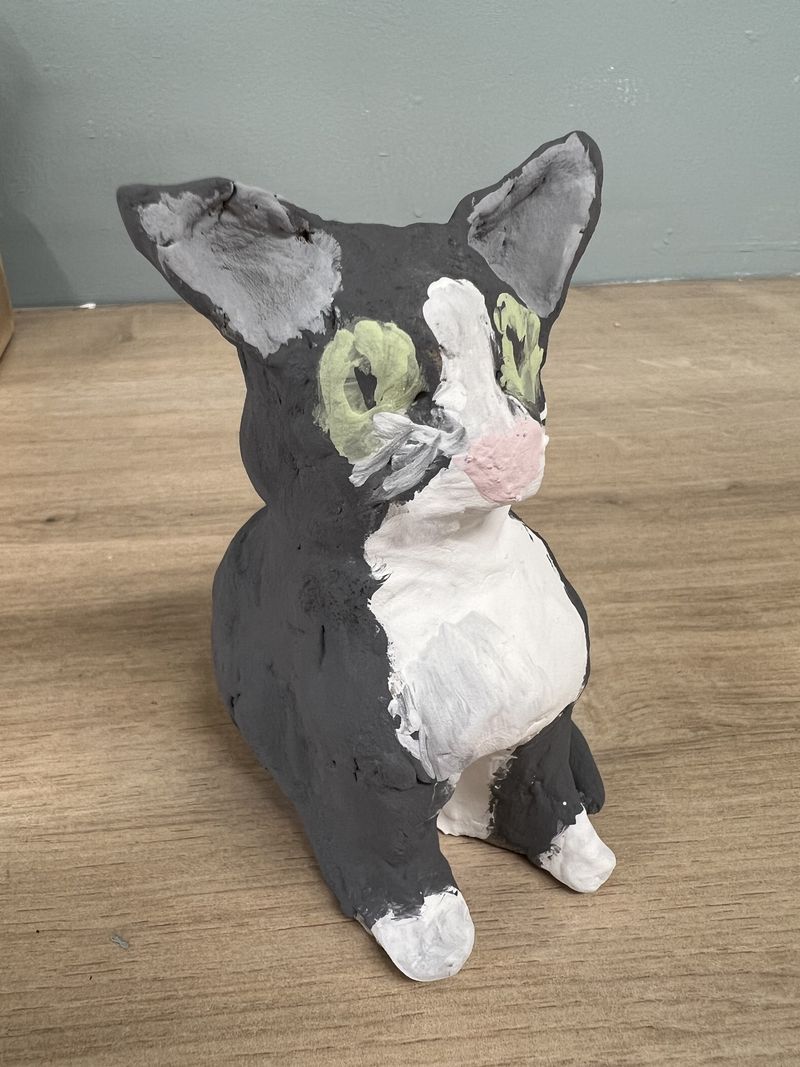 Clay model of a black and white cat with green eyes